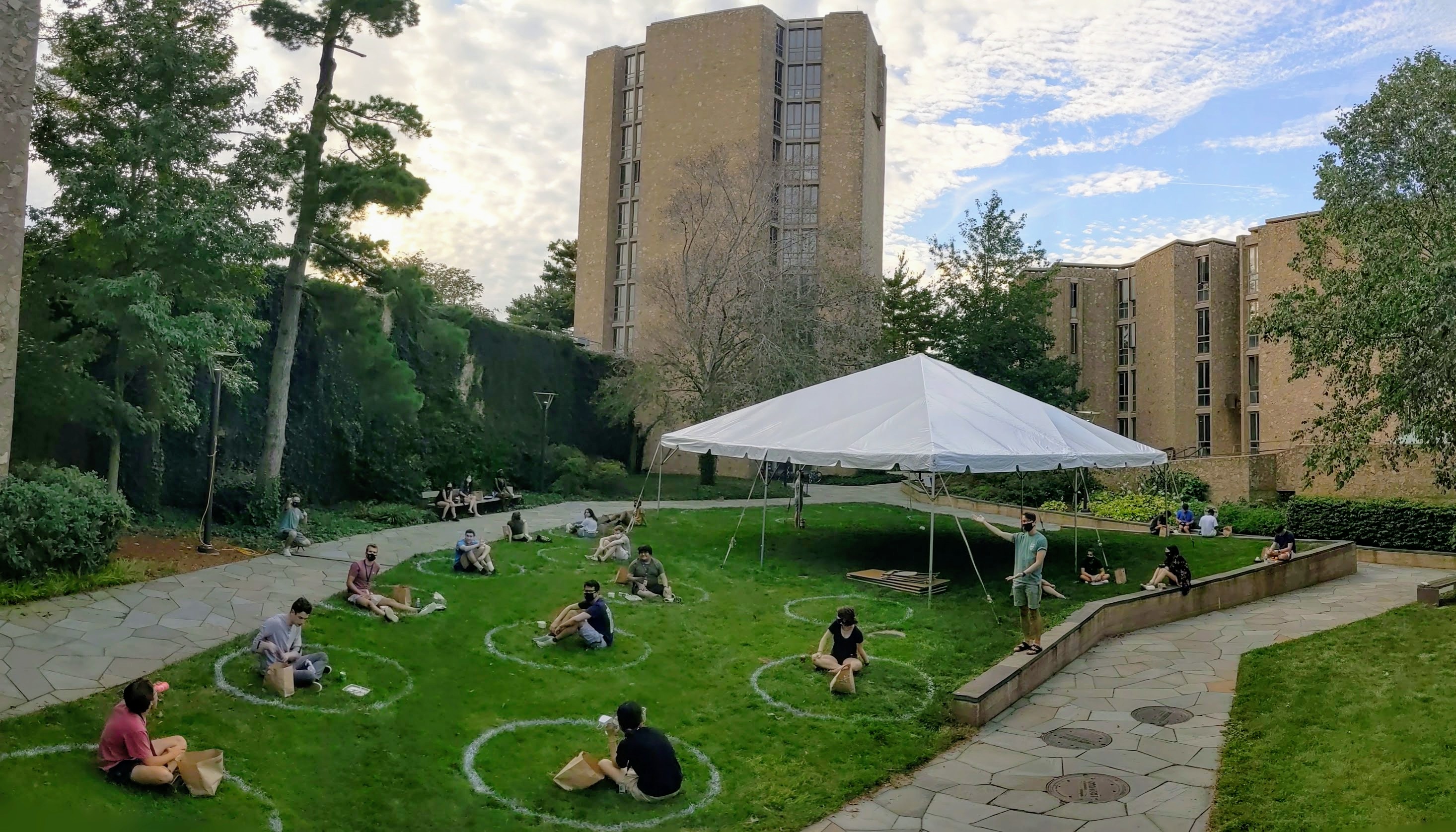 At the beginning of the Fall semester, students sit in spray-painted social-distancing circles in the Stiles Courtyard. In the background, the Stiles Tower is entirely void of students for the term. Captured 8/24/2020.
